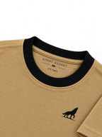 Close up of black ribbed crew neckline, Kiddy Kloset neck label and black wolf logo on camel brown tee