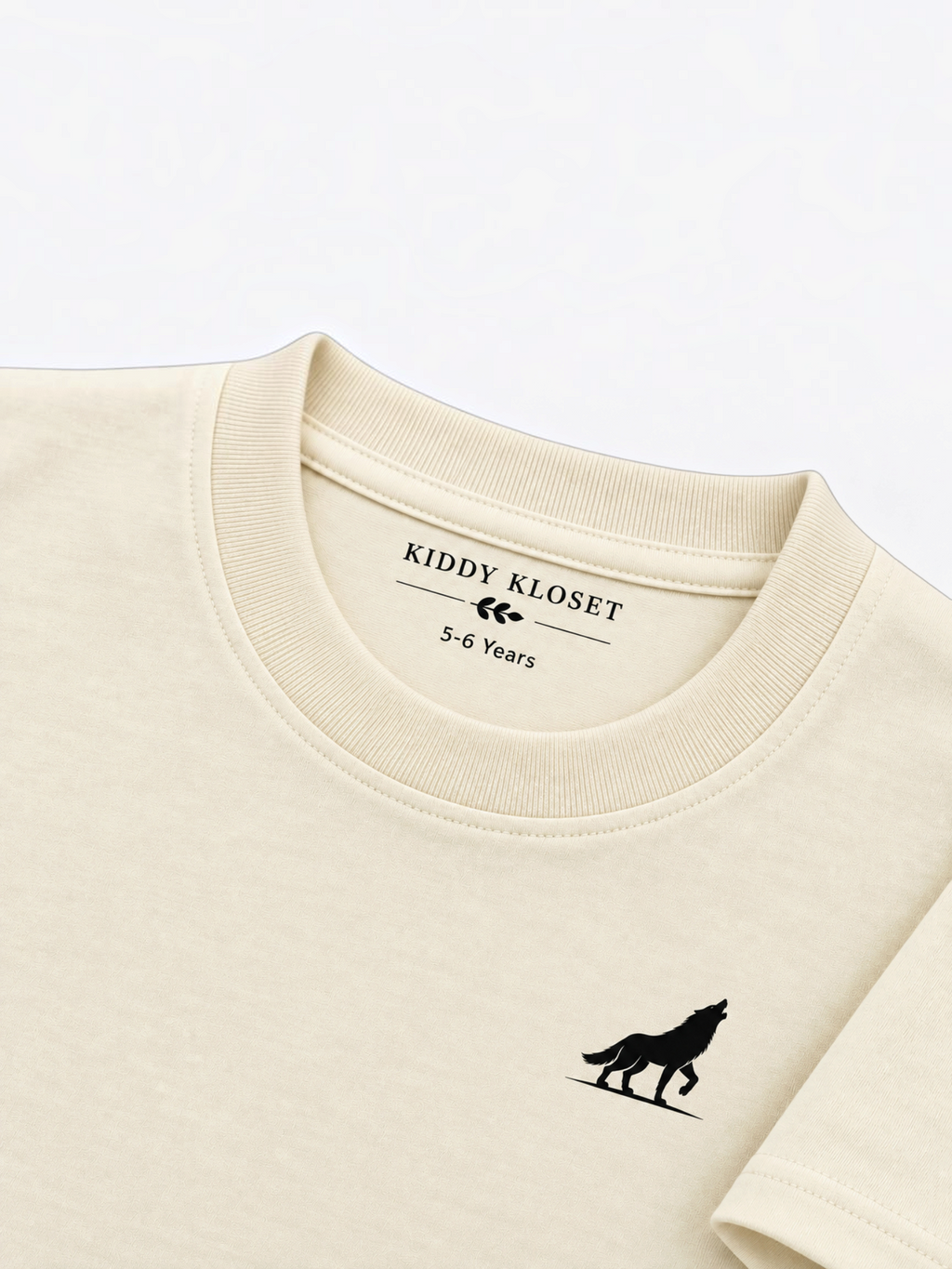 Close up of tonal cream ribbed crew neckline, Kiddy Kloset neck label and black wolf logo