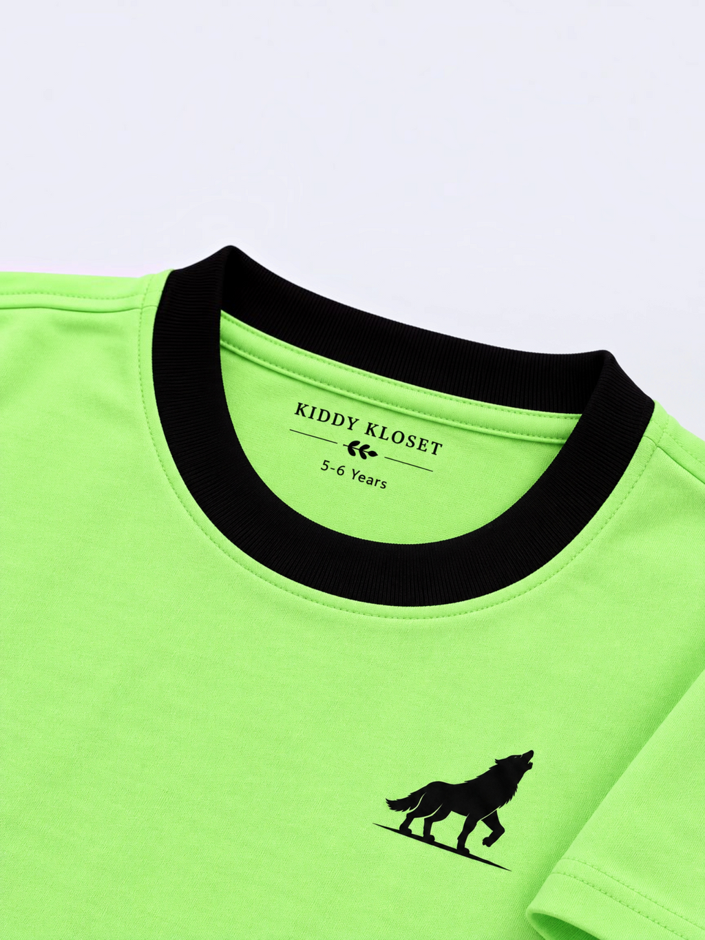 Close up of black ribbed crew neckline, Kiddy Kloset neck label and black wolf logo on lime green tee