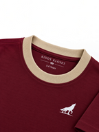 Close up of beige ribbed crew neckline, branded neck print and white wolf logo on burgundy tee