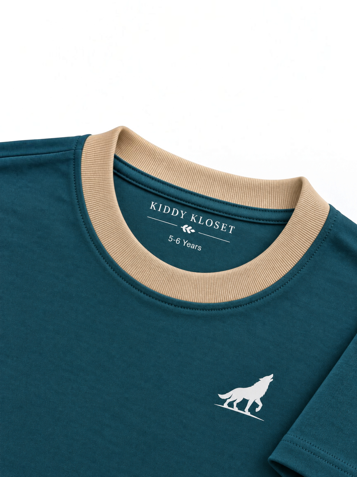 Close up of beige ribbed crew neckline, branded neck print and white wolf logo on teal tee