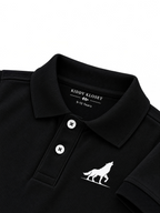 Close up of black polo collar, two-button placket and white wolf logo on kids black polo shirt