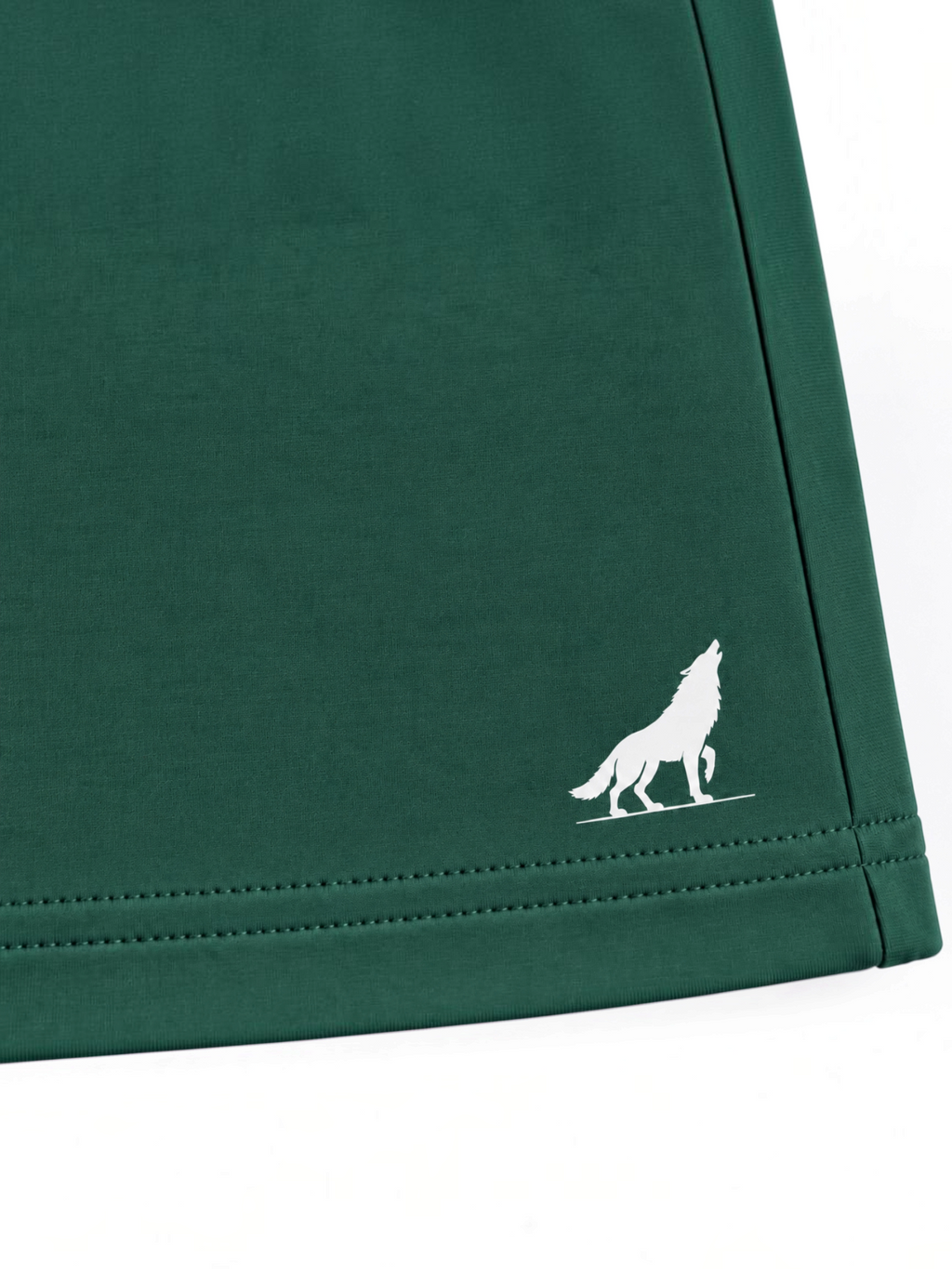 Close up of white wolf logo and stitched hem on kids forest green shorts