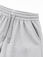 Close up of elasticated waistband, grey drawcord and side pocket on kids grey shorts