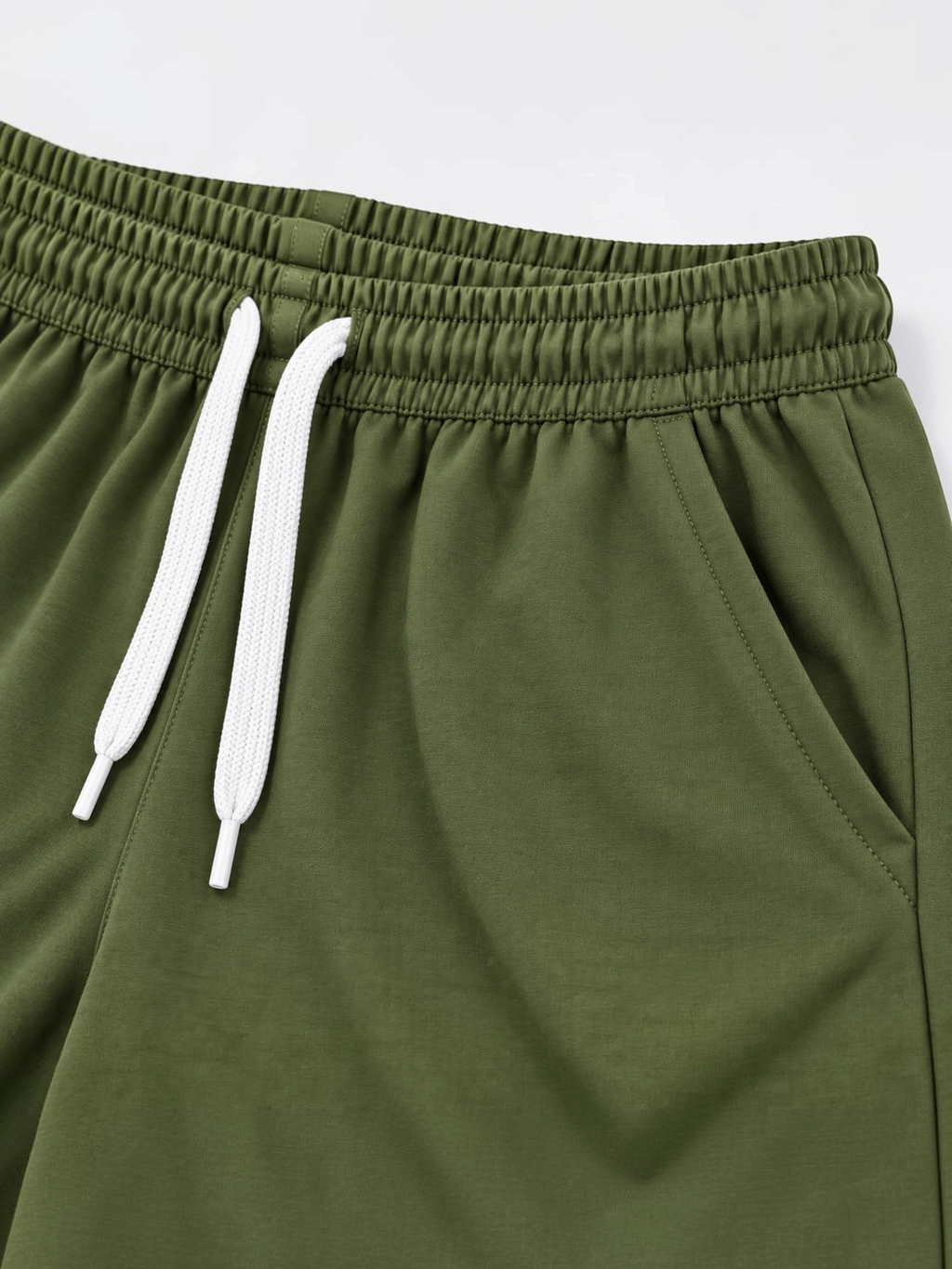 Close up of elasticated waistband, white drawcord and side pocket on kids olive shorts