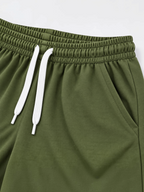 Close up of elasticated waistband, white drawcord and side pocket on kids olive shorts