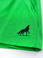 Close up of black wolf logo and stitched hem on kids parrot green shorts