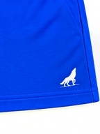 Close up of white wolf logo and stitched hem on kids royal blue shorts